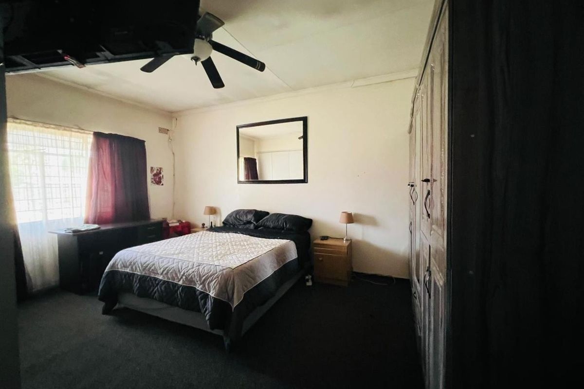 A bedroom featuring built-in cupboards and a ceiling fan, requiring cosmetic updates to the ceiling and flooring to enhance its appeal.