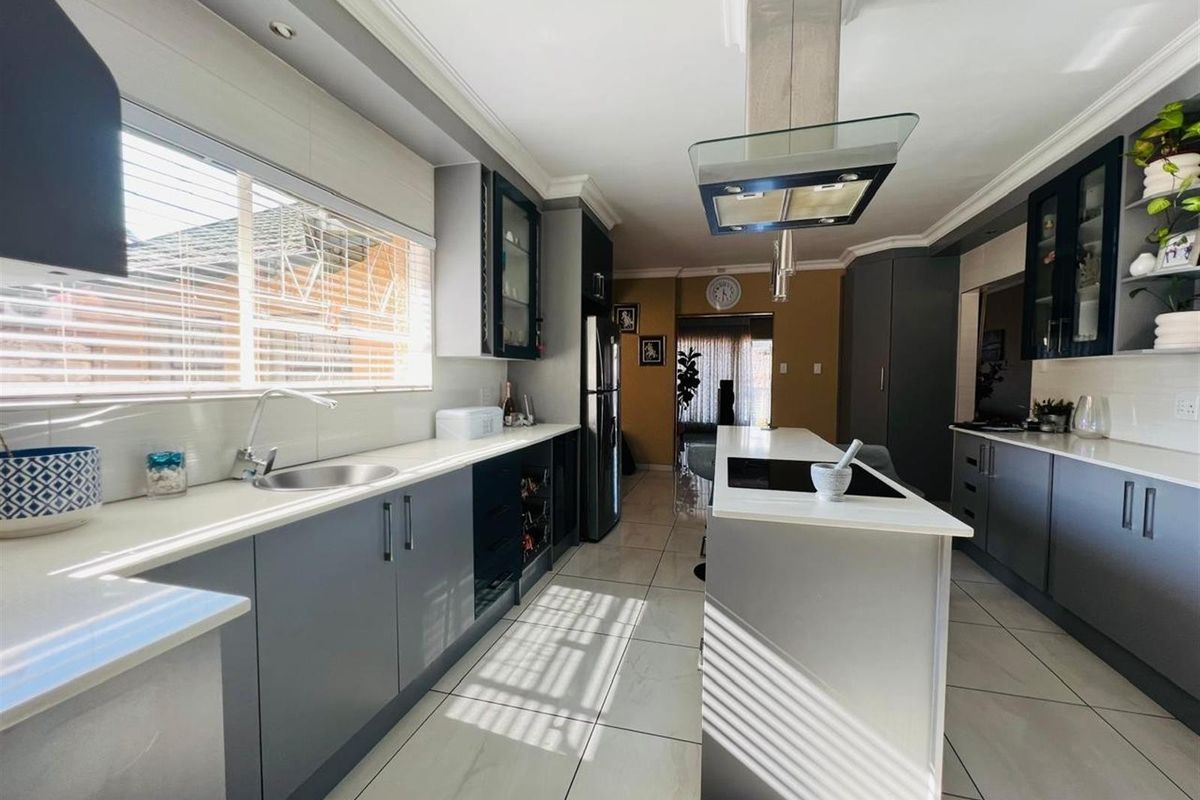 Modern kitchen featuring a central island with an integrated hob, sleek cabinetry, stone countertops, and high-quality finishes throughout.