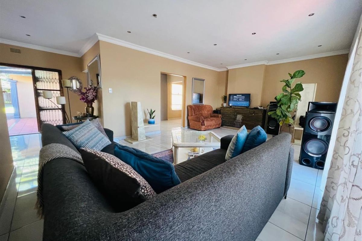 A spacious living room featuring tiled flooring, recessed downlighting, and neutral wall tones, providing a comfortable and functional area for relaxation.
