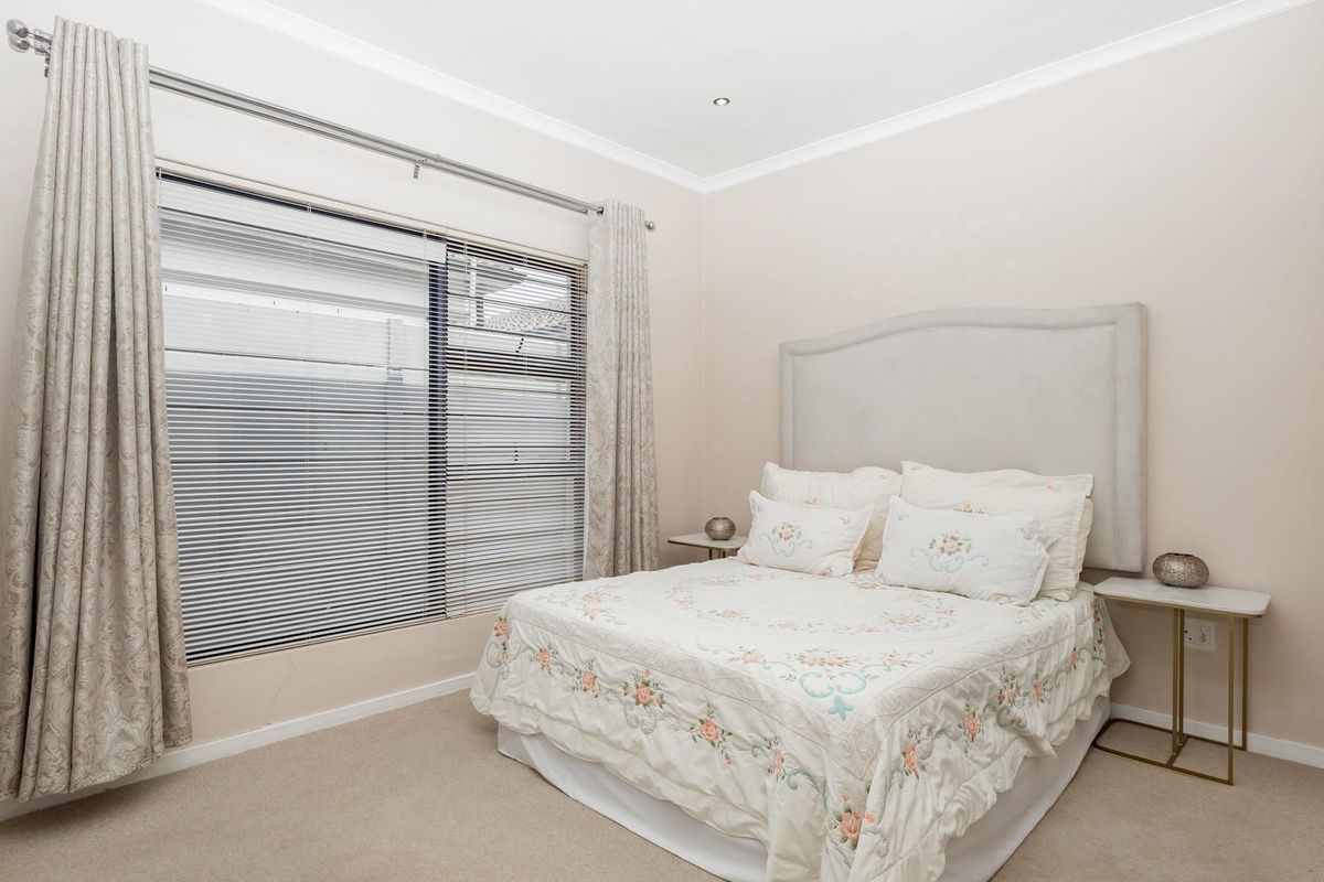 A well-maintained bedroom featuring neutral wall tones, carpeted flooring, recessed downlighting, and venetian blinds.