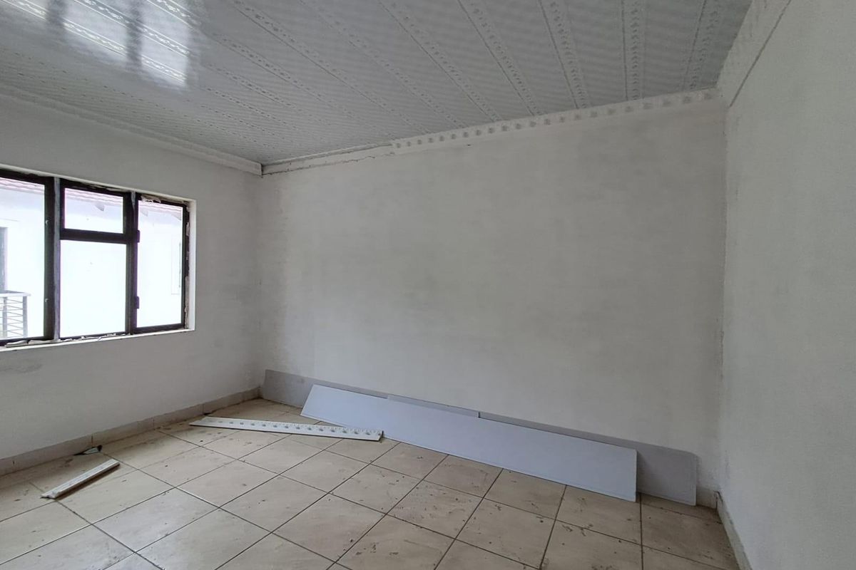 An empty, unfinished room featuring tiled flooring, a textured ceiling, and a window, currently undergoing renovation or maintenance.