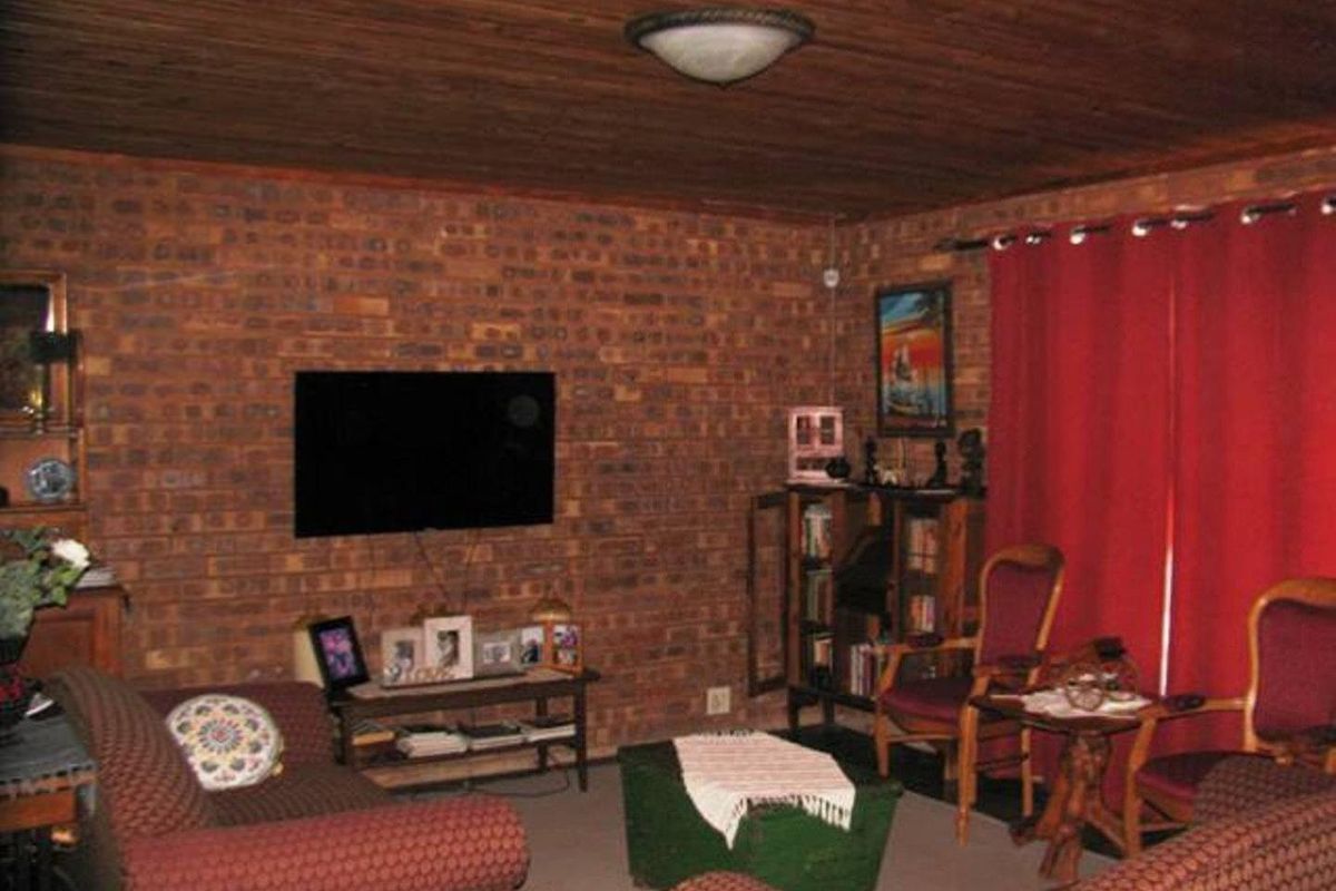 A rustic living room featuring exposed face-brick walls and a timber-clad ceiling, creating a traditional farm-style aesthetic.