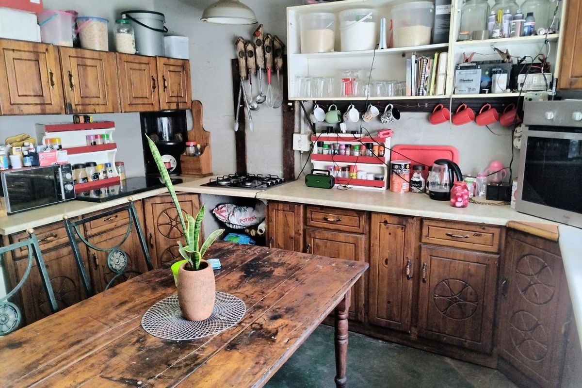 A rustic farm-style kitchen featuring traditional wooden cabinetry, integrated gas hob, built-in oven, and ample open shelving for storage.
