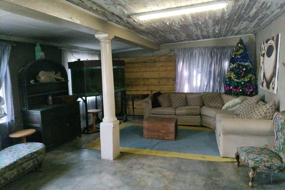 Spacious living area featuring a concrete floor, structural support column, and a rustic timber-paneled wall with a weathered ceiling finish.