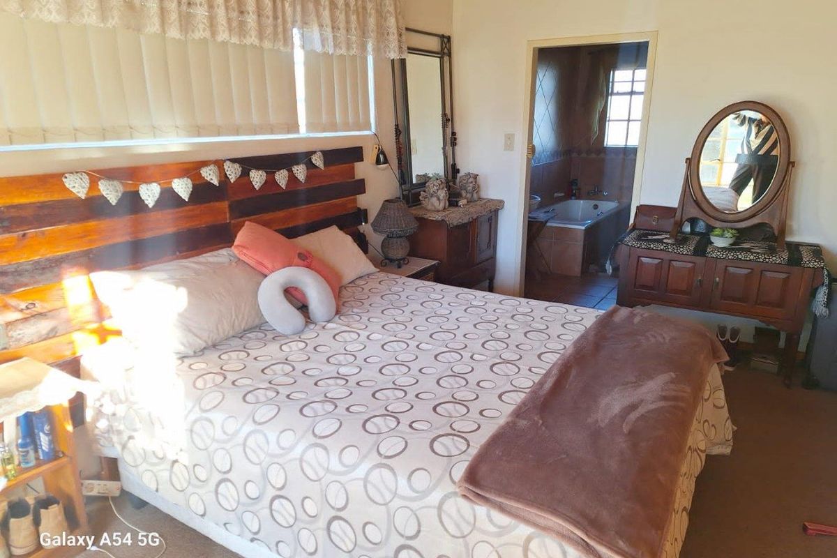 A bedroom featuring a built-in headboard and an en-suite bathroom with a bathtub visible through the doorway.