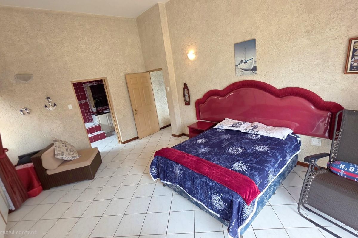 Spacious bedroom featuring tiled flooring, textured wall finishes, and an adjoining en-suite bathroom with tiled accents.
