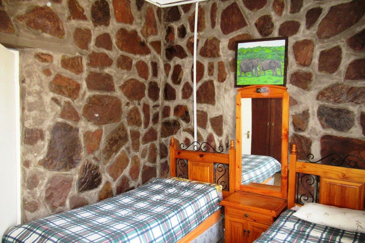 A bedroom featuring rustic natural stone wall cladding and a built-in wooden wardrobe.