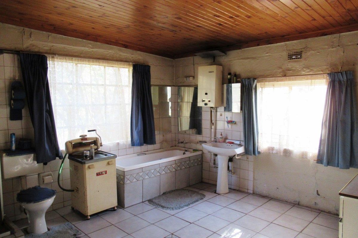 A dated bathroom featuring a pedestal basin, built-in bathtub, and wood-paneled ceiling, requiring modernization to improve functionality and aesthetic appeal.
