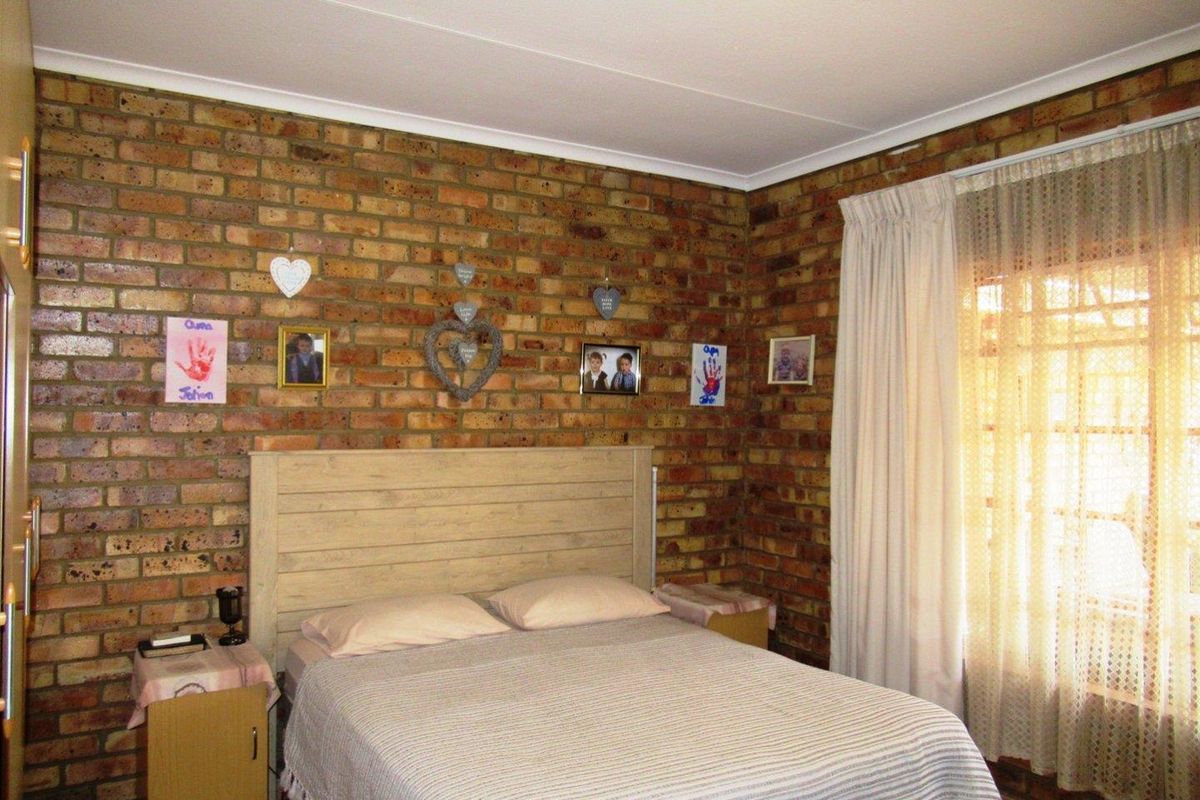 A bedroom featuring an exposed brick feature wall and coved ceiling, providing a rustic aesthetic with natural light from the window.
