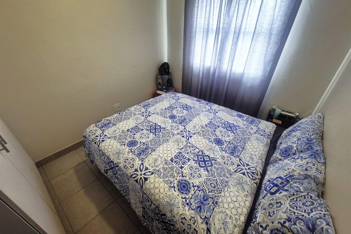 A compact bedroom featuring tiled flooring and a built-in wardrobe, providing a functional and straightforward living space.