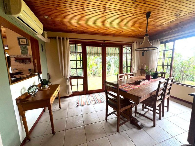 A dining room featuring a warm timber ceiling, tiled floors, and direct access to the garden through classic french doors.