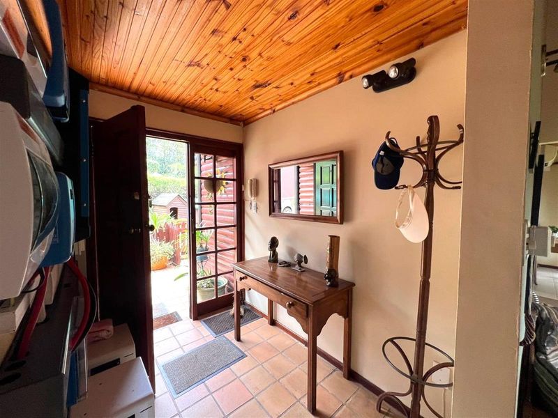 Welcoming entrance hall featuring warm timber tongue and groove ceiling, tiled flooring, and a classic french door leading to the exterior.