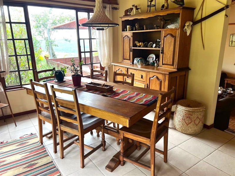 A dining room featuring tiled flooring, a large window with natural light, and a central pendant light fixture.