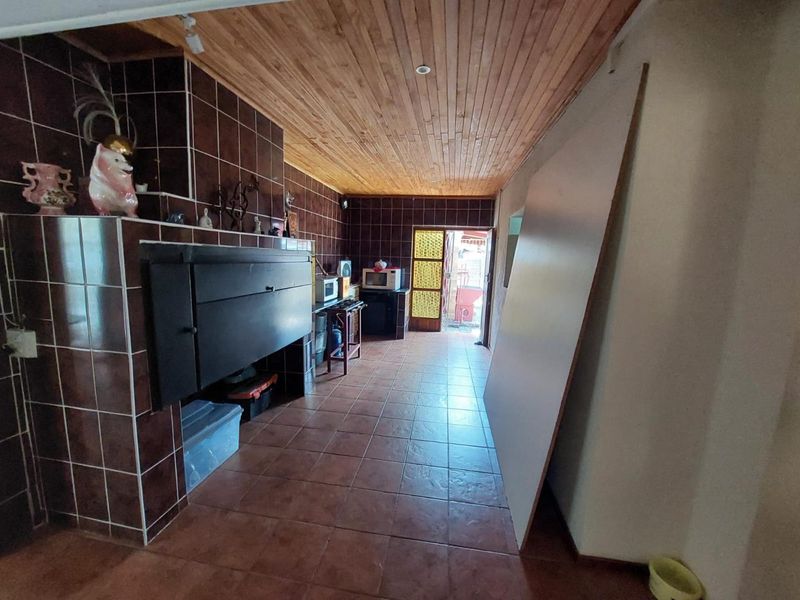 A utility space or secondary kitchen area featuring dark tiled walls, a built-in fireplace or oven unit, and a timber-clad ceiling.