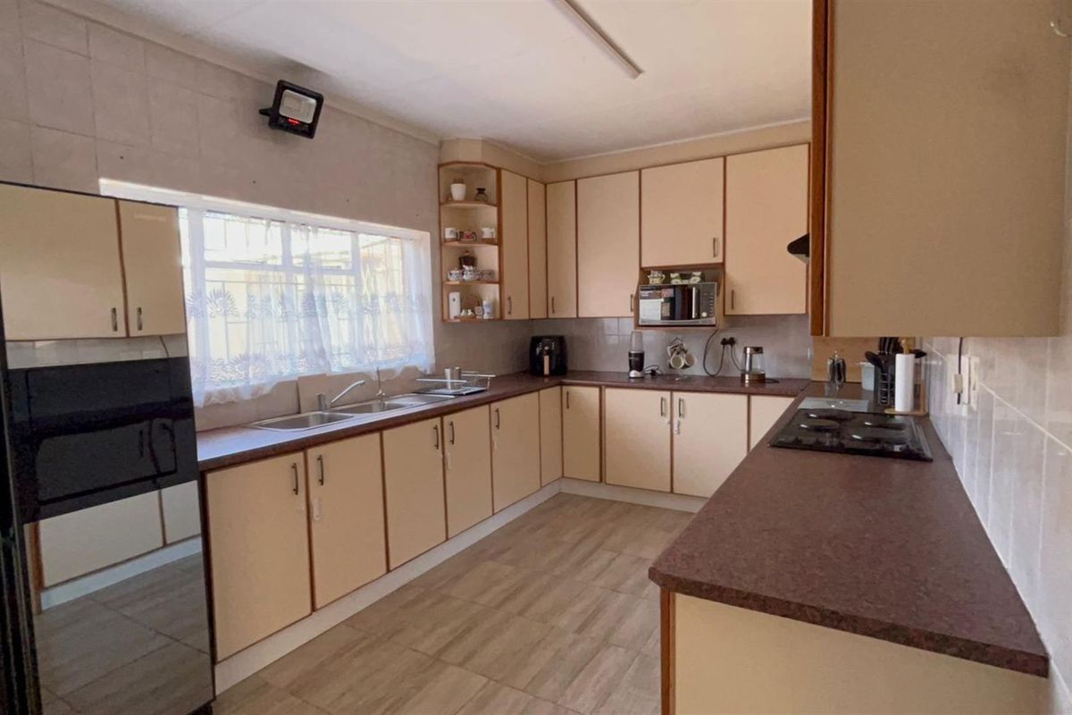 A functional kitchen featuring ample cabinetry, a double sink, built-in hob, and tiled flooring, offering a practical layout for daily meal preparation.