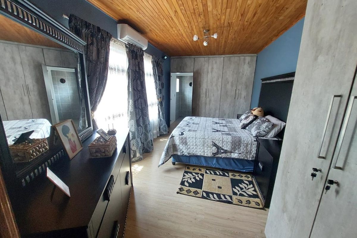 A bedroom featuring wood-paneled ceilings, built-in cupboards, laminate flooring, and a wall-mounted air conditioning unit.