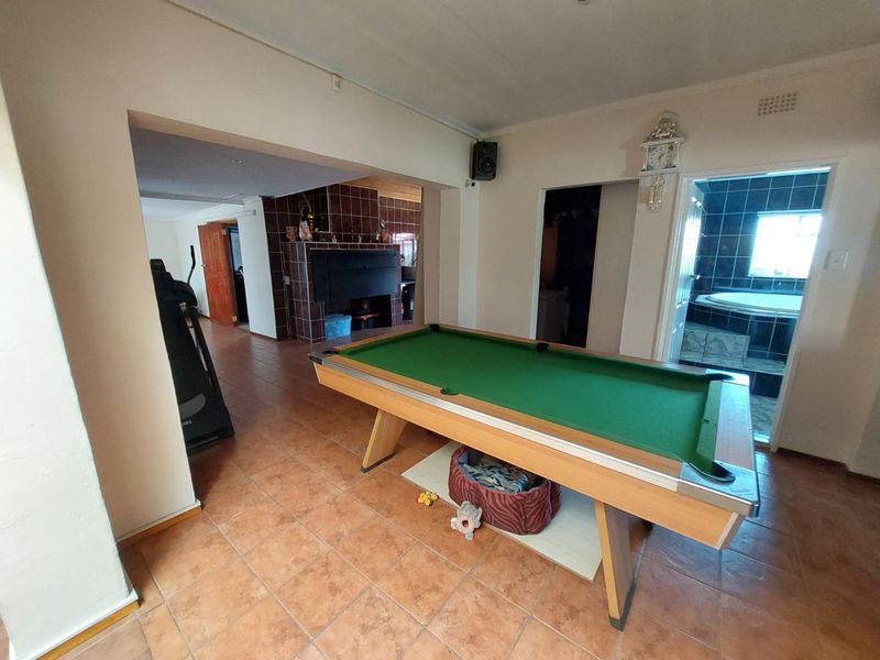 Spacious living area featuring terracotta floor tiles, a built-in tiled fireplace, and direct access to an adjacent bathroom.