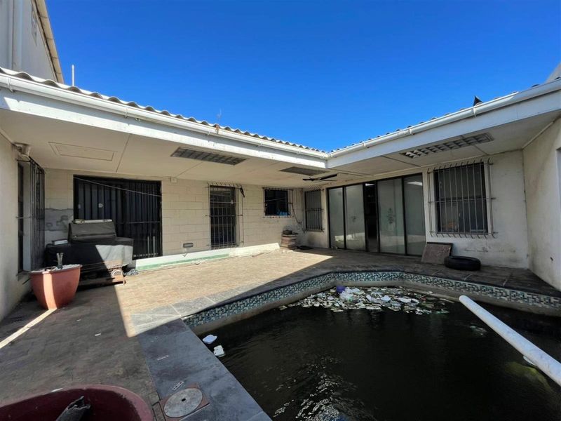 Outdoor pool area featuring a covered patio and sliding door access, currently requiring significant maintenance and cleaning of the pool and exterior surfaces.