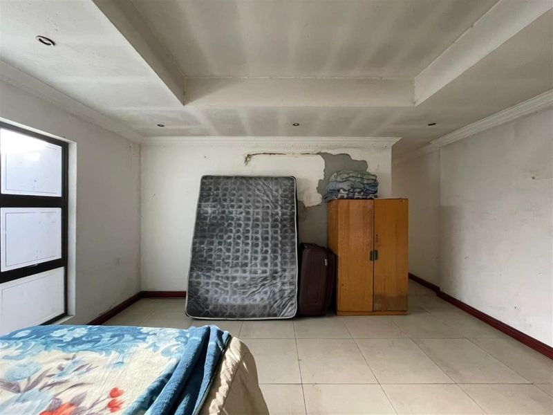 A bedroom featuring tiled flooring and a recessed ceiling, currently requiring repairs to the wall plaster and ceiling finishes.