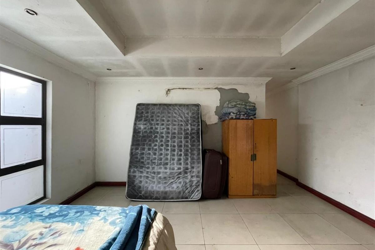 A bedroom featuring tiled flooring and a recessed ceiling, currently requiring repairs to the wall plaster and ceiling finishes.