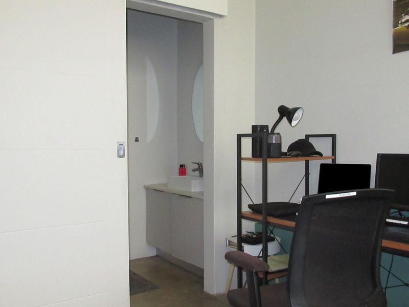 A bedroom featuring a sliding door leading to an en-suite bathroom with a modern vanity and vessel sink.