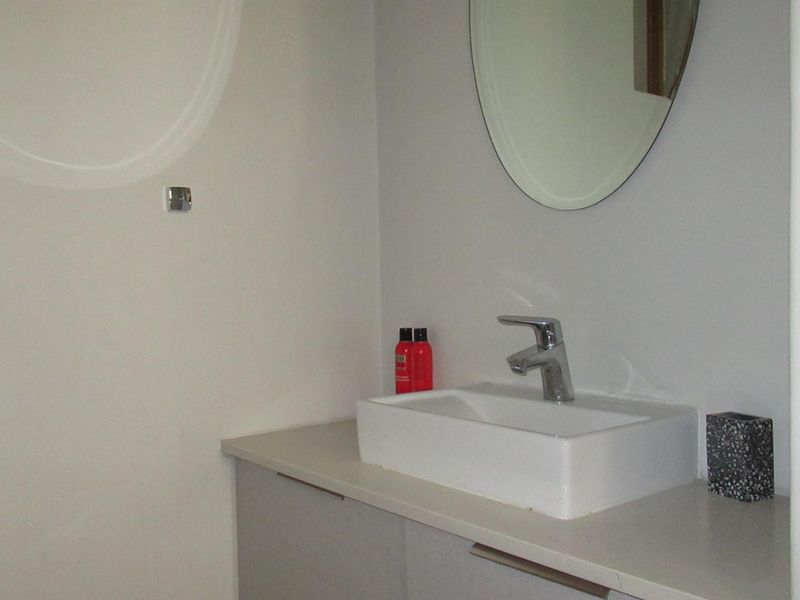 A clean bathroom vanity area featuring a modern vessel sink, chrome faucet, and a wall-mounted mirror.