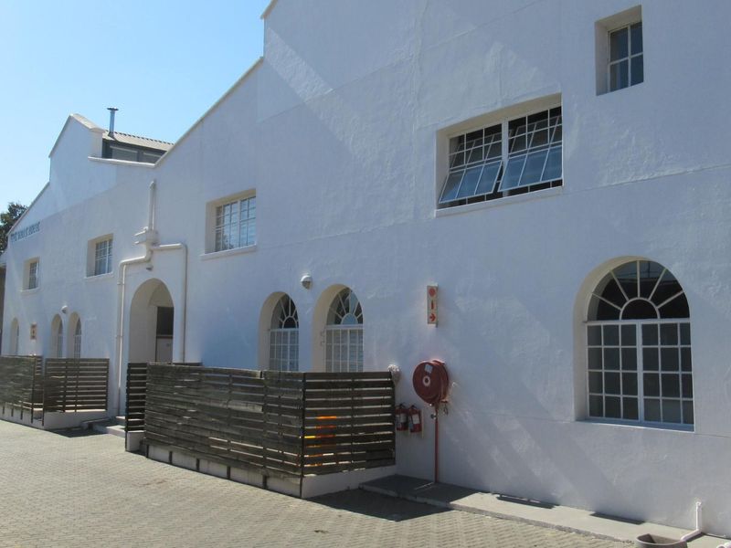 Exterior view of a white-painted apartment building featuring arched windows, paved driveway access, and integrated fire safety equipment.