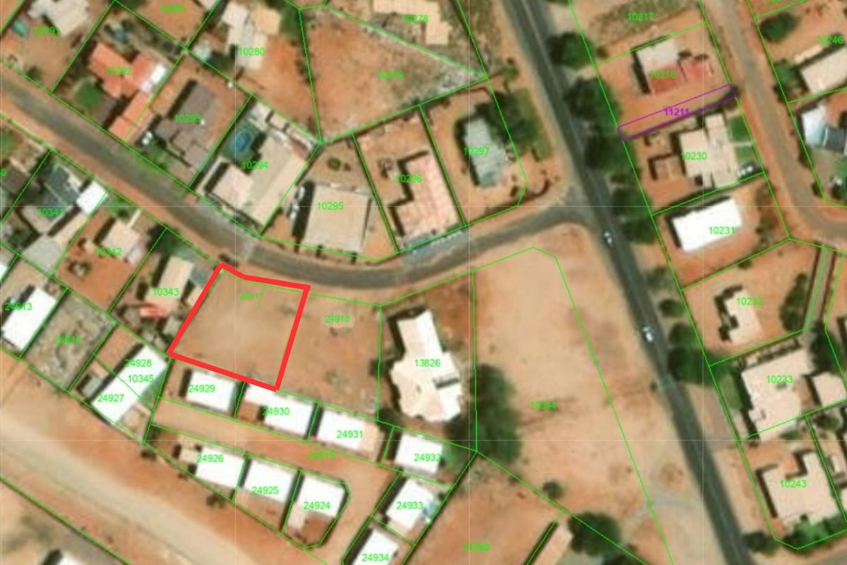 An aerial view of a vacant residential plot highlighted in red, situated within an established suburban neighborhood.