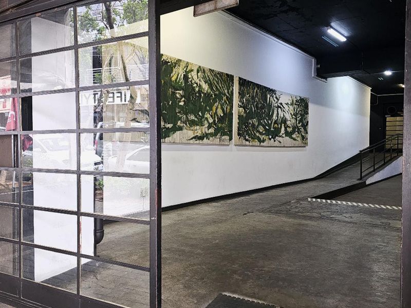An industrial-style building entrance featuring a metal-framed glass door, concrete ramp access, and minimalist wall lighting.