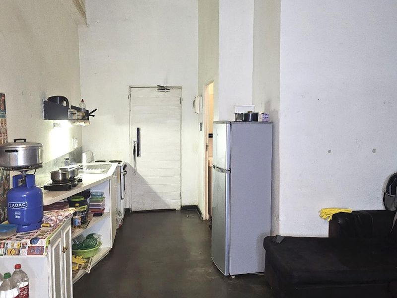 A basic kitchen area featuring a simple counter, sink, and stove, requiring cosmetic updates and finishing to improve the overall aesthetic and functionality.