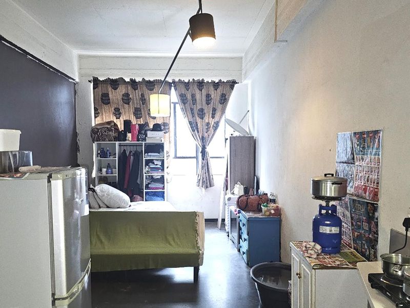 Compact open-plan studio apartment featuring a combined living and sleeping area with basic finishes and natural light.