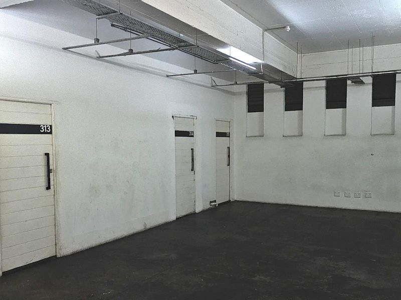 An industrial-style utility space featuring exposed cable management, concrete flooring, and multiple numbered access doors, suitable for storage or workshop use.