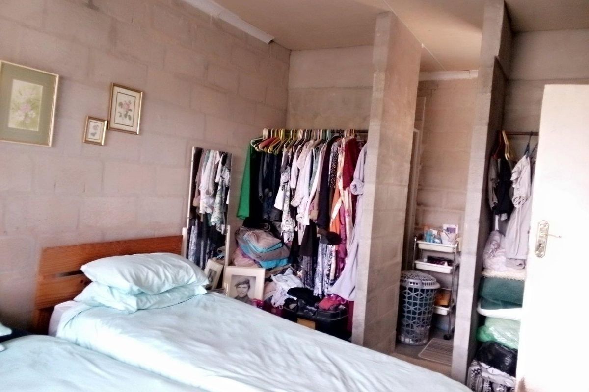 A bedroom featuring exposed concrete block walls and built-in partition walls creating an open-concept closet area.