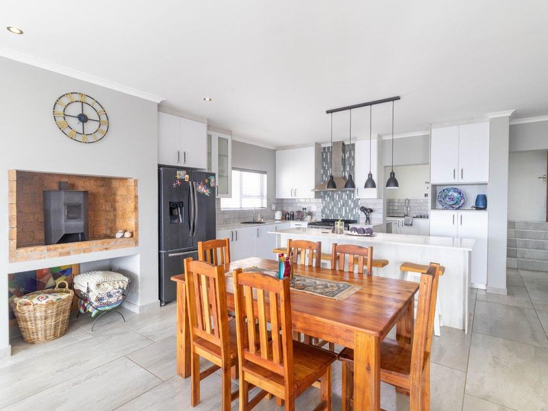 Spacious open-plan living and kitchen area featuring a built-in fireplace, modern cabinetry, kitchen island, and tiled flooring throughout.