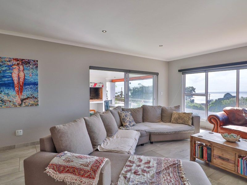 Spacious living room featuring tiled flooring, recessed lighting, and large windows with ocean views, providing seamless access to an outdoor patio area.