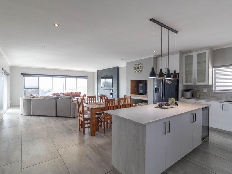 Spacious open-plan living area featuring a modern kitchen with island, dining space, and a comfortable lounge area with fireplace and large sliding doors.