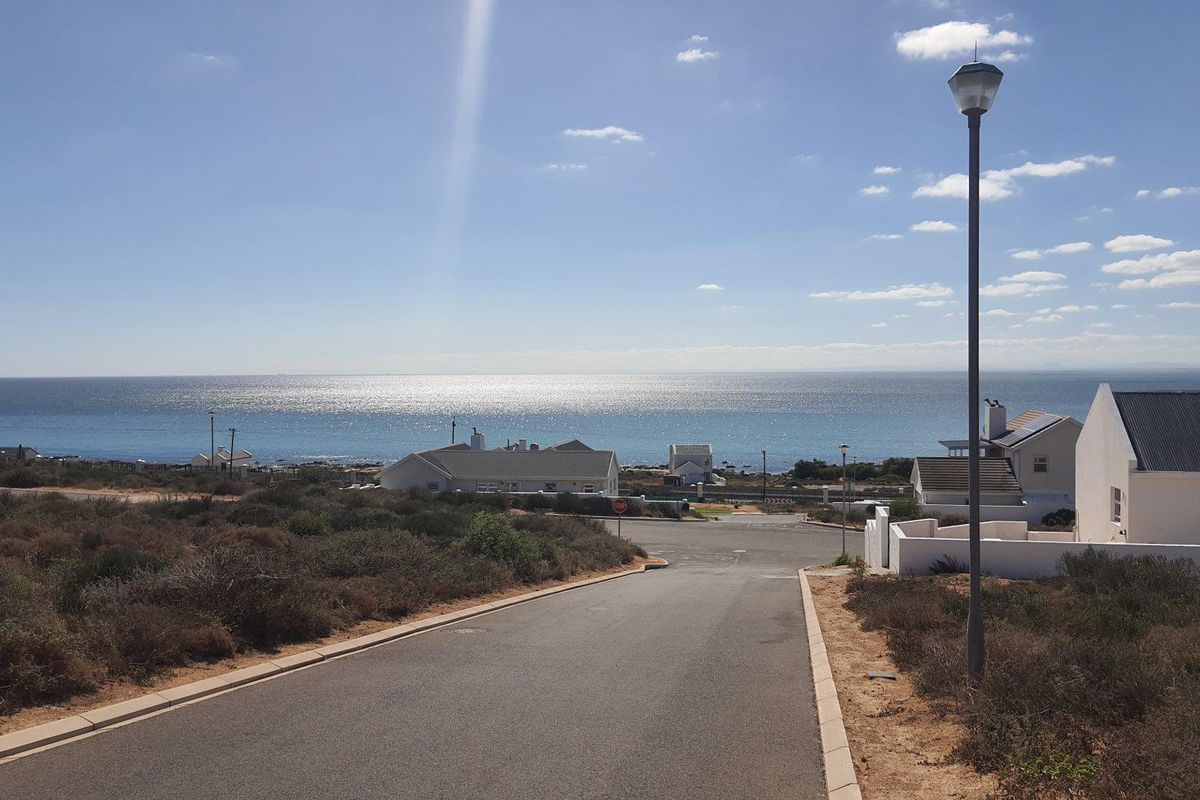 A view looking down a paved residential street towards the ocean, showcasing the coastal location and surrounding neighborhood landscape.