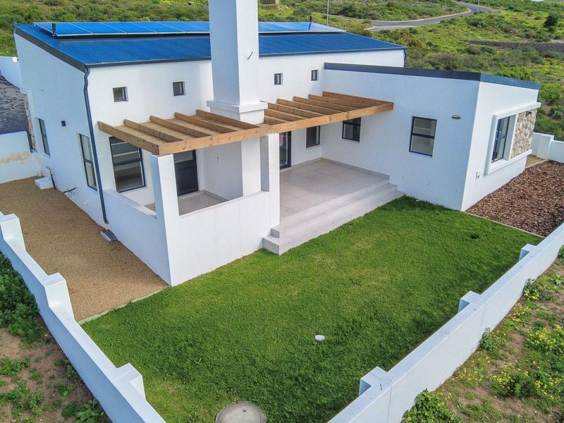 Aerial view of the rear elevation featuring a tiled patio with a timber pergola, solar panels on the roof, and a private lawn area.