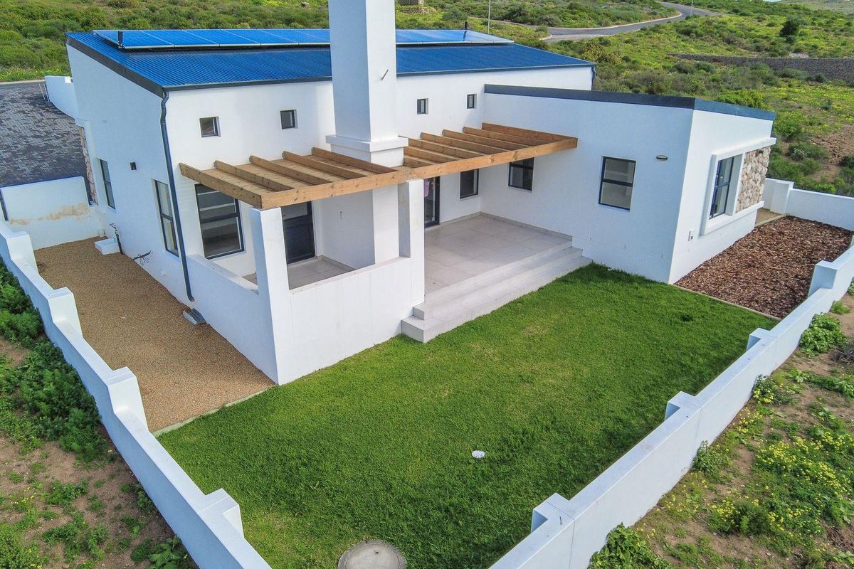 Aerial view of the rear elevation featuring a tiled patio with a timber pergola, solar panels on the roof, and a private lawn area.