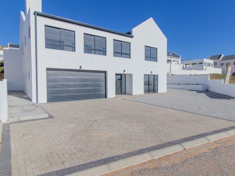 Modern double-storey residence featuring a clean white facade, paved driveway, and integrated garage, situated in a contemporary residential estate.