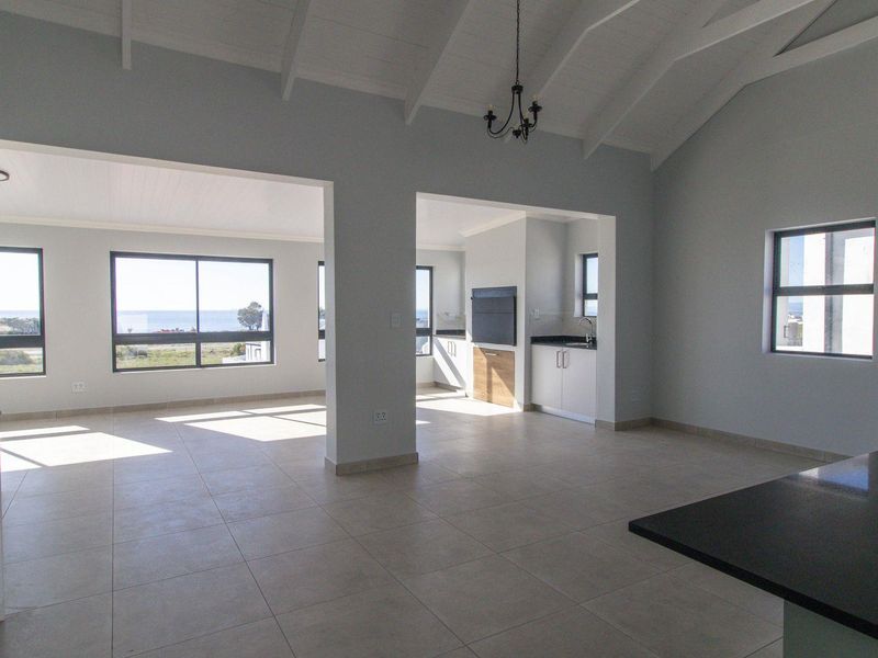 Spacious open-plan living area featuring vaulted ceilings, tiled floors, built-in cabinetry, and large windows with scenic views.
