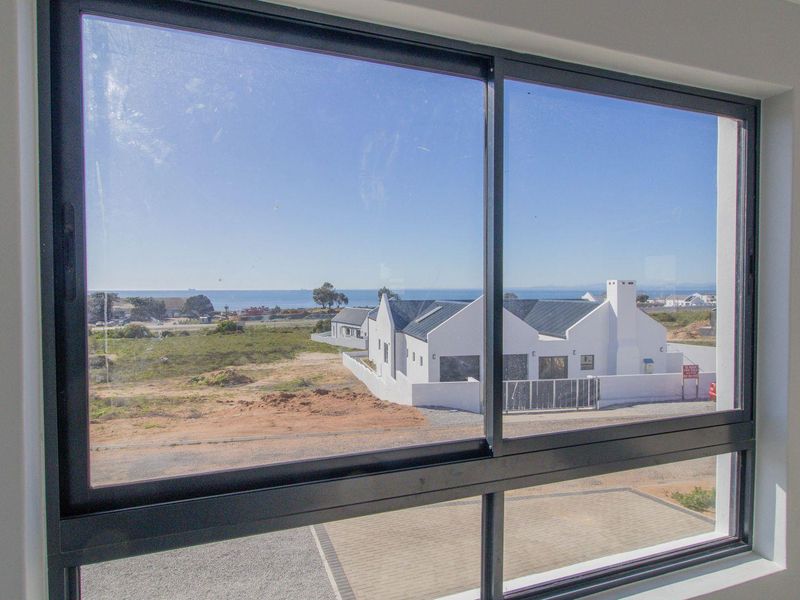A clear view of the surrounding coastal landscape and neighbouring properties captured through a modern aluminium-framed window.
