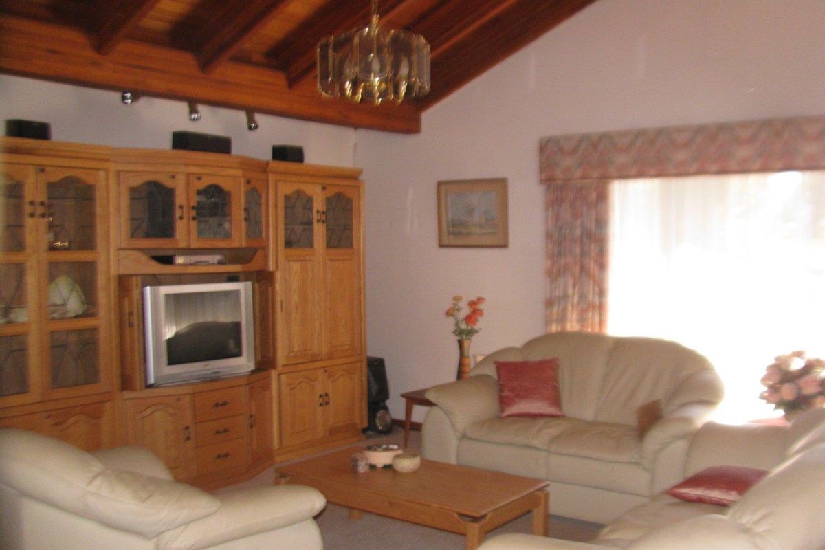 A living room featuring a vaulted timber-beamed ceiling and a large built-in wooden cabinetry unit.