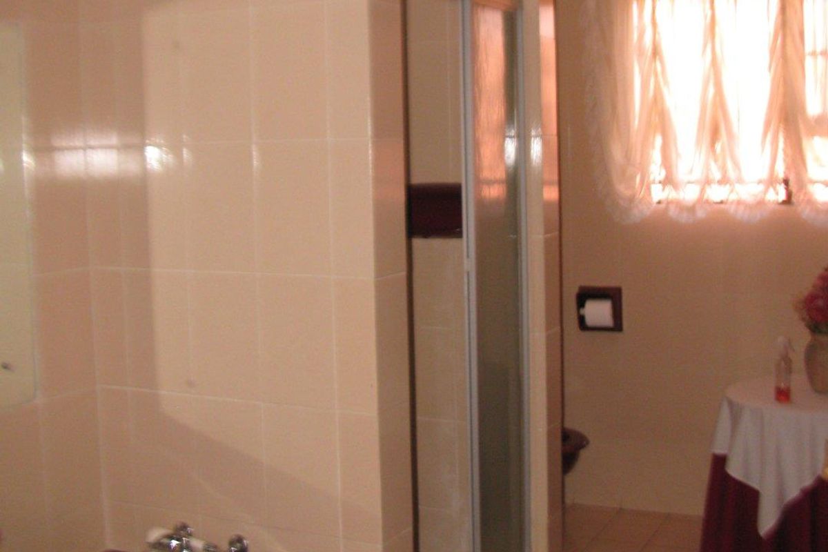 A functional bathroom featuring a built-in bathtub, a separate glass-enclosed shower, and tiled wall finishes.