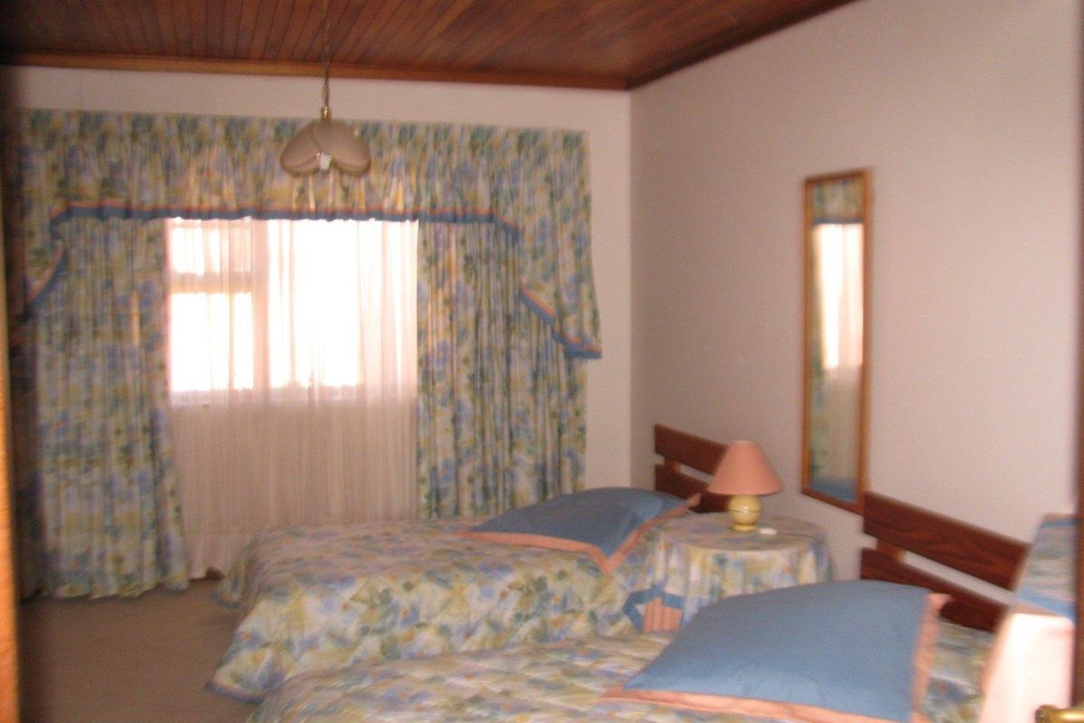A bedroom featuring a timber-paneled ceiling and carpeted flooring, providing a traditional and functional sleeping space.