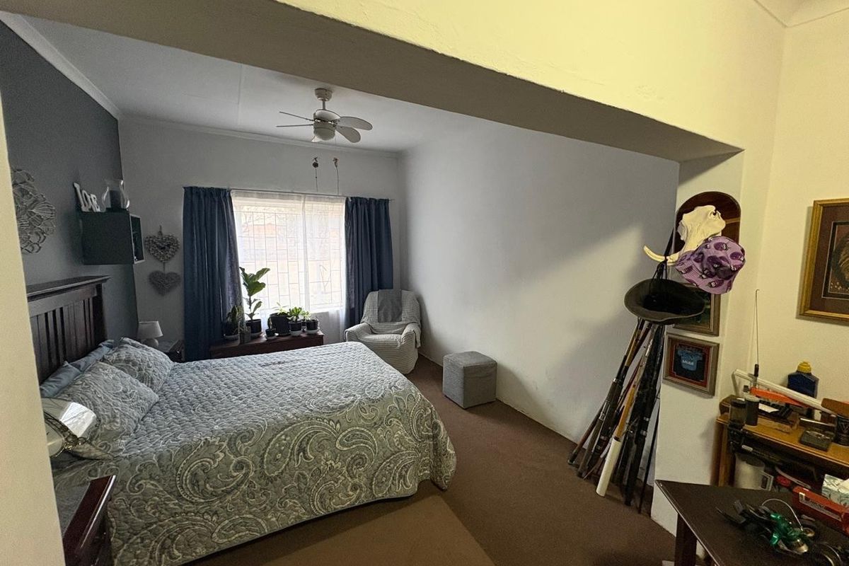 A bedroom featuring a ceiling fan and neutral wall finishes, offering a functional space with potential for modern updates.