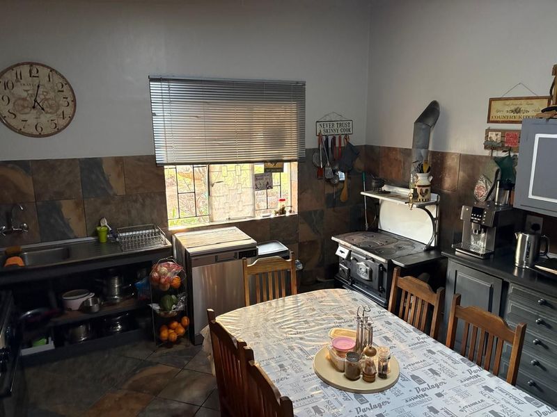 Rustic farm-style kitchen featuring a traditional cast iron wood-burning stove, slate tile backsplash, and functional workspace with integrated sink.