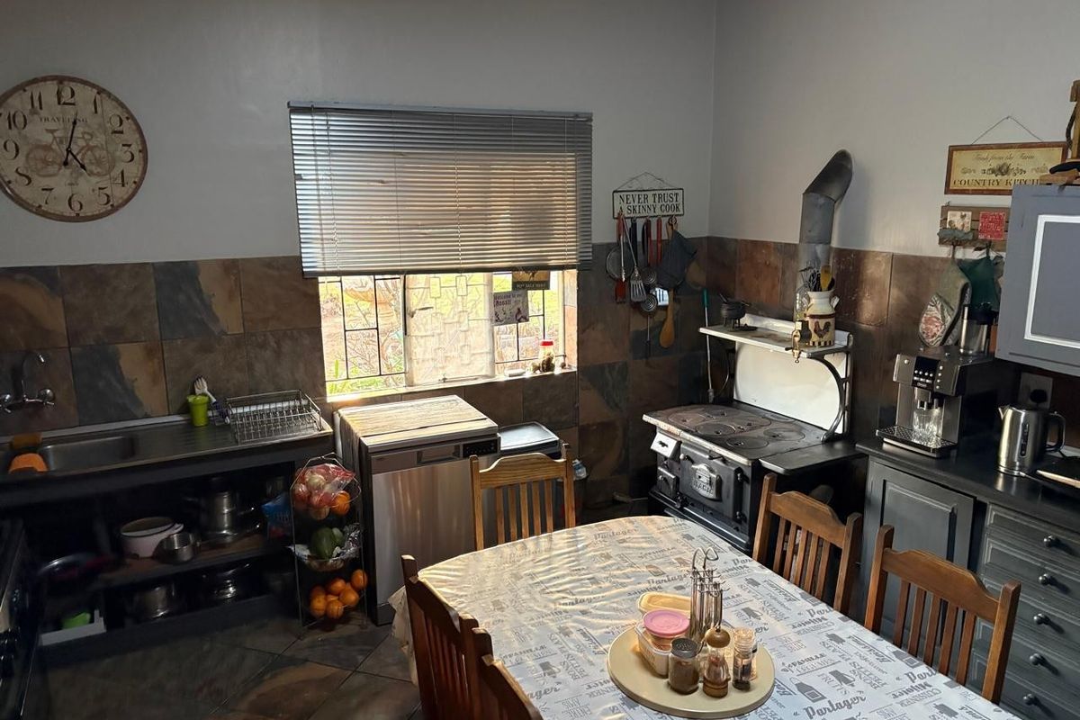 Rustic farm-style kitchen featuring a traditional cast iron wood-burning stove, slate tile backsplash, and functional workspace with integrated sink.
