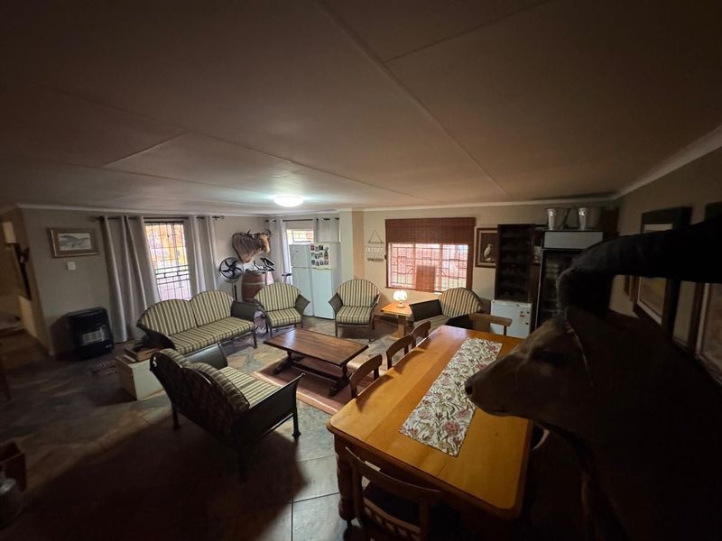 Spacious open-plan living and dining area featuring tiled flooring and security gates, offering a functional layout for family living.