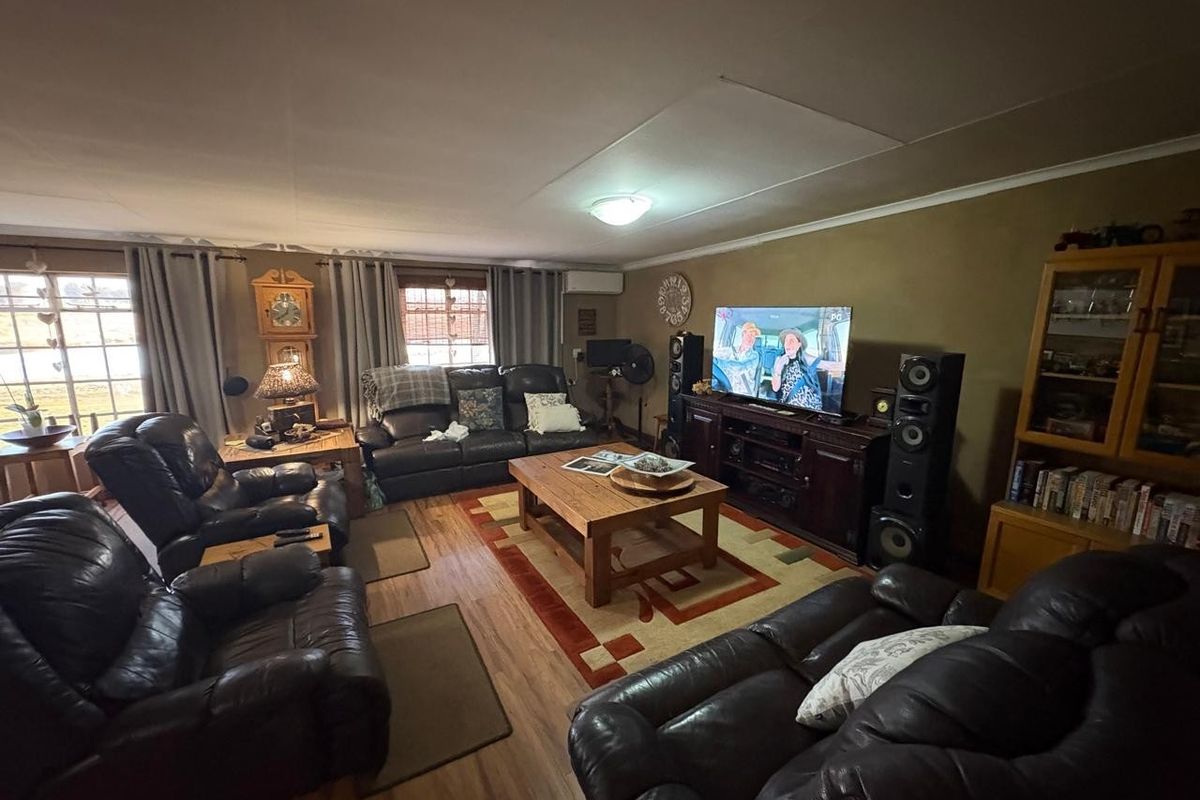 A spacious living room featuring laminate flooring and a wall-mounted air conditioning unit, offering a comfortable and functional family space.